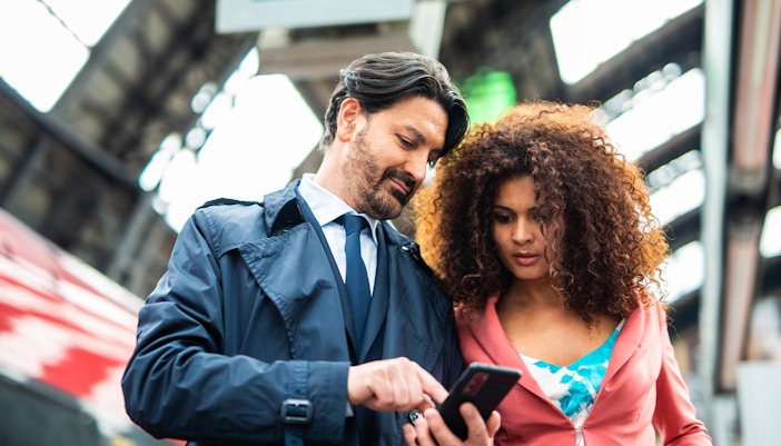 man and women checking train tickets on phone