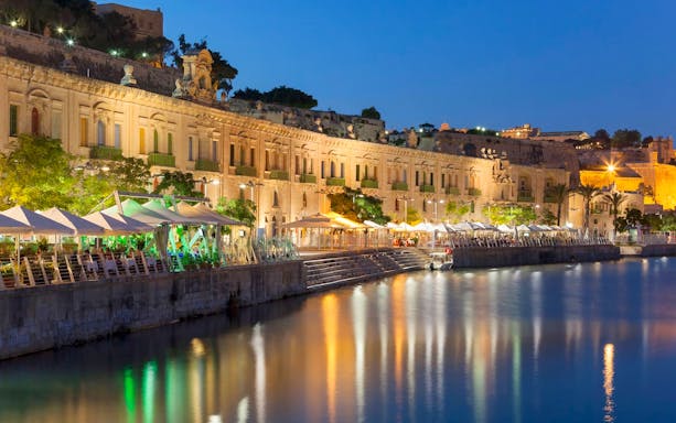 Historic waterfront buildings illuminated at night during a 3-hour guided tour in Malta.