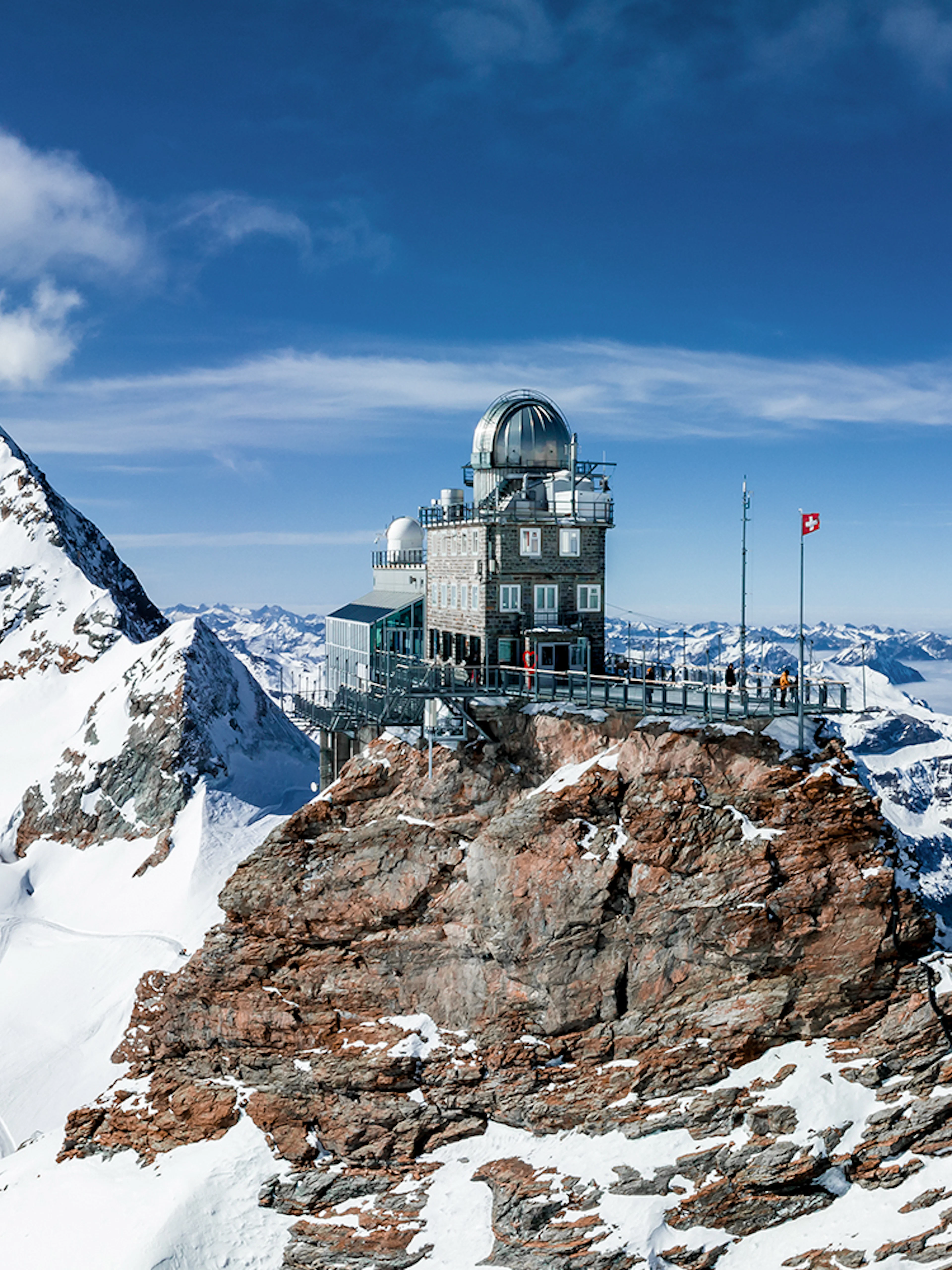 Jungfraujoch observatory on snowy peak, Swiss Alps, with panoramic mountain views.