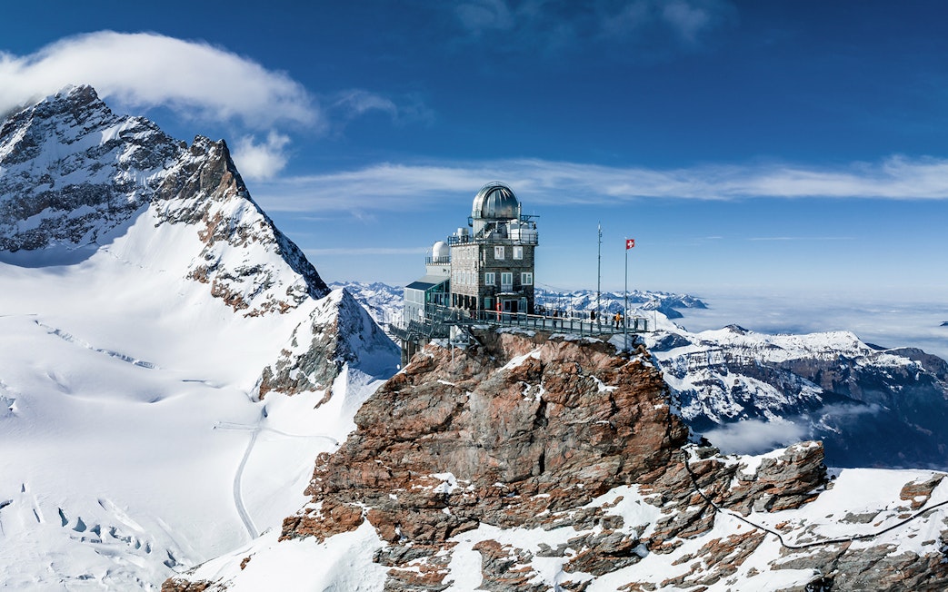 Jungfraujoch observatory on snowy peak, Swiss Alps, with panoramic mountain views.