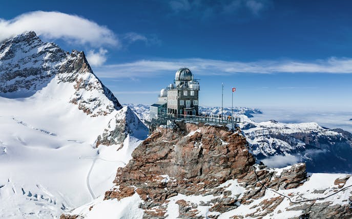 Jungfraujoch observatory on snowy peak, Swiss Alps, with panoramic mountain views.