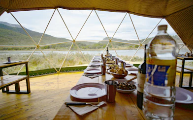 Dining setup inside a dome with view of Tierra del Fuego National Park landscape.