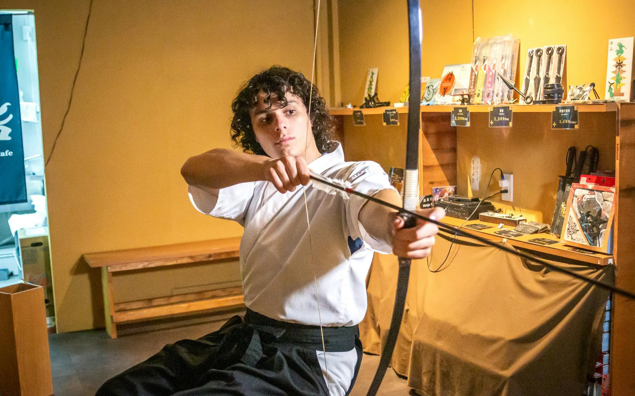 Kyoto archery participant drawing bow in traditional Japanese setting.