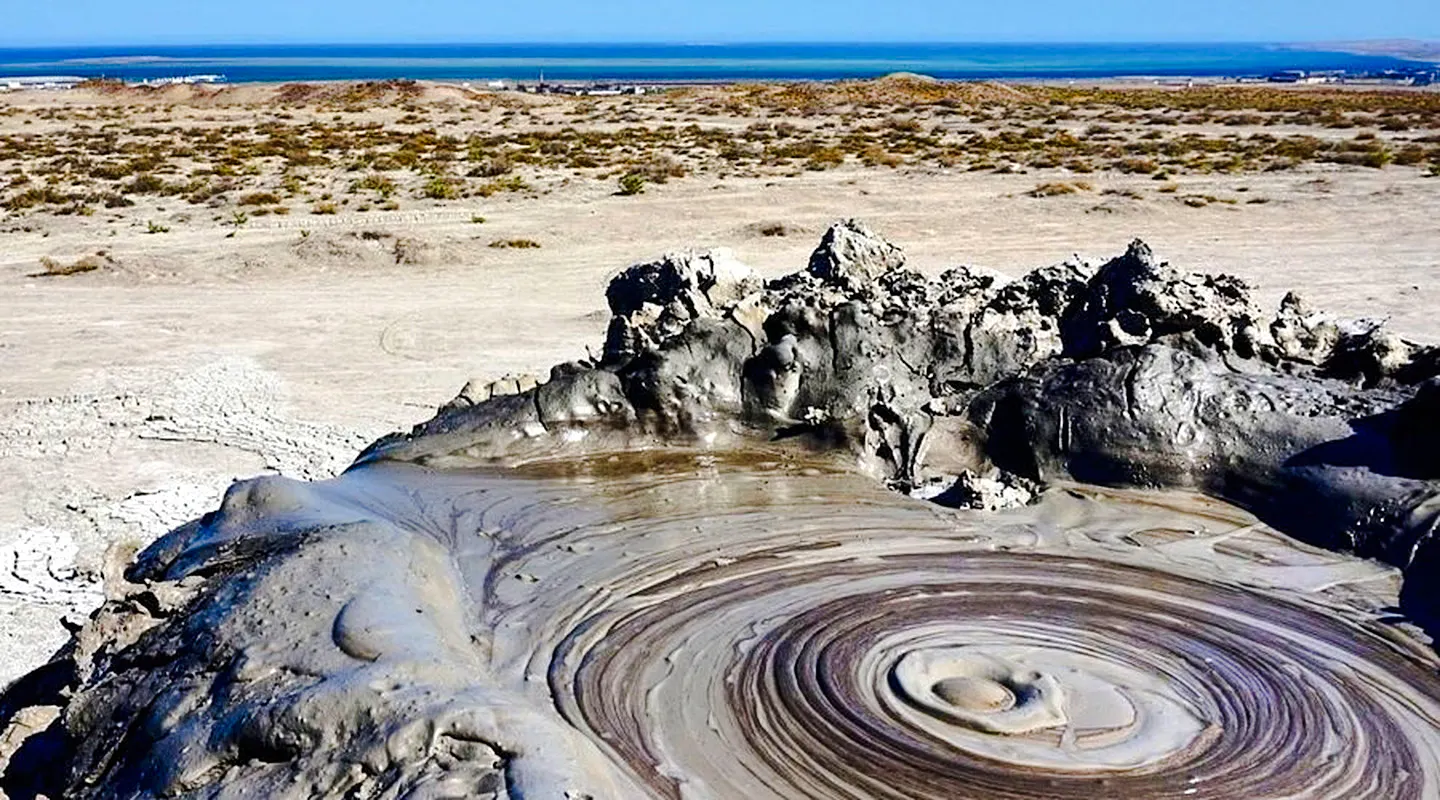 Mud volcano in Gobustan National Park with distant view of Baku, Azerbaijan.