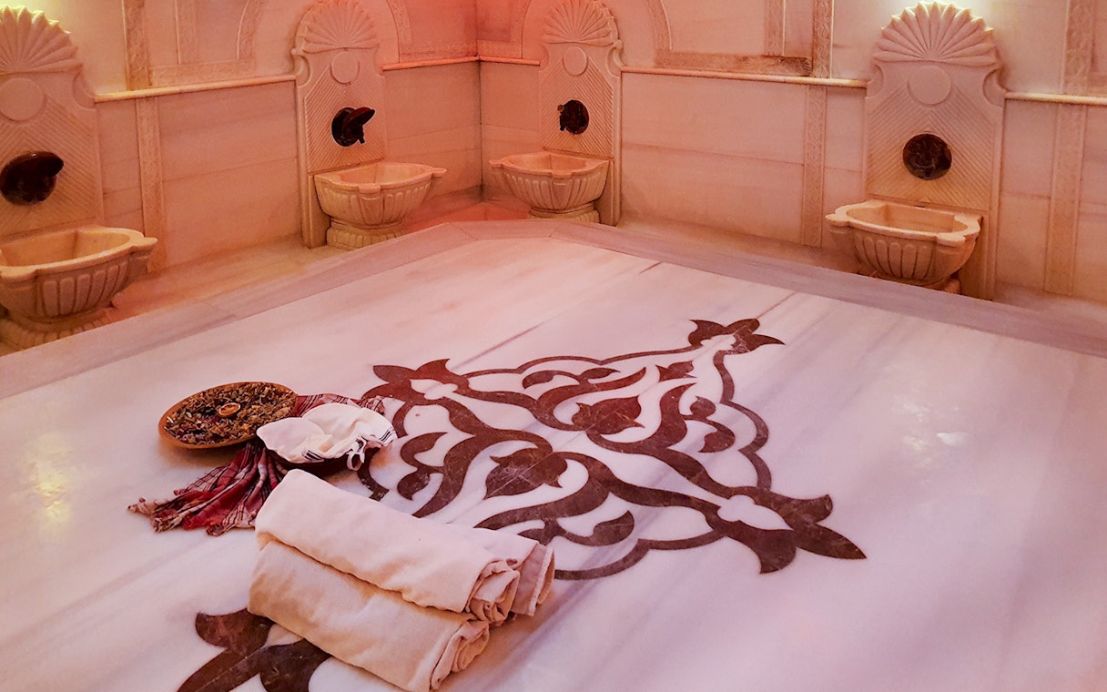 Acemoglu Hamam interior with marble basins and ornate floor design, 15th-century Turkish bath.