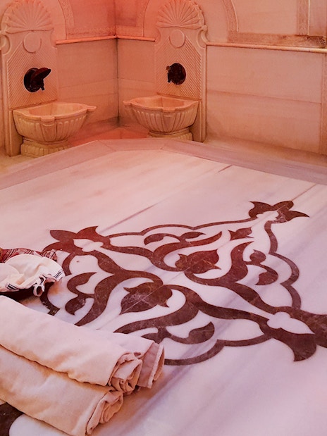 Acemoglu Hamam interior with marble basins and ornate floor design, 15th-century Turkish bath.