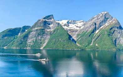Boats on Geirangerfjord with snow-capped mountains, Ålesund-Geiranger-Ålesund tour.