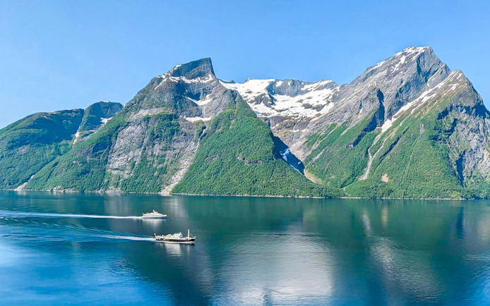 Boats on Geirangerfjord with snow-capped mountains, Ålesund-Geiranger-Ålesund tour.