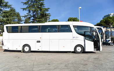 Bus for Tirana Airport transfer service parked at a station.