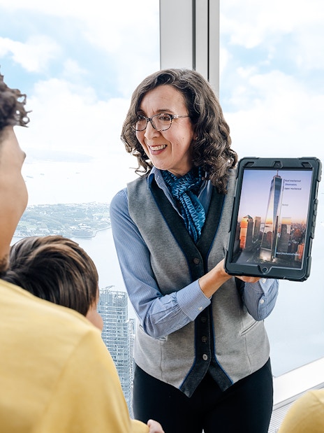 Guide showing One World Observatory view on tablet to visitors.