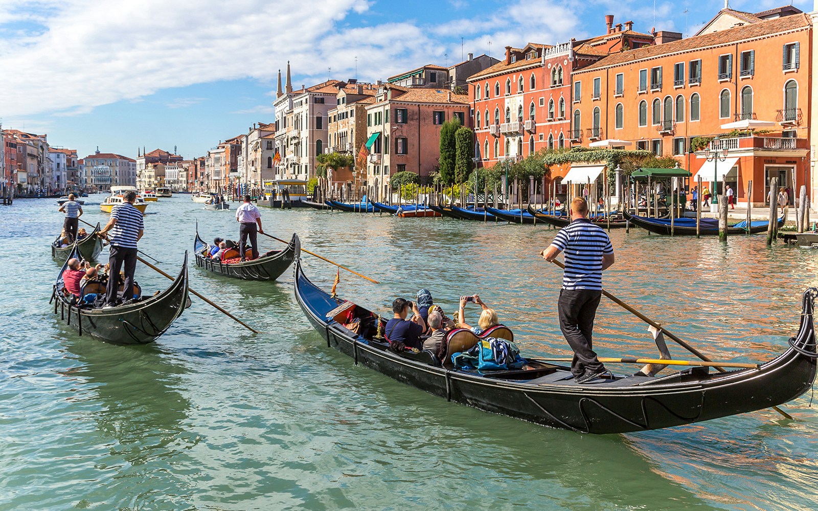 Gondolas navigating the Grand Canal in Venice, Italy with historic buildings in the background.