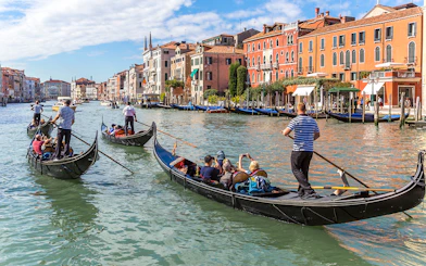 Gondolas navigating the Grand Canal in Venice, Italy with historic buildings in the background.