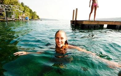 Swimming in Shala River near a wooden dock, surrounded by lush greenery.