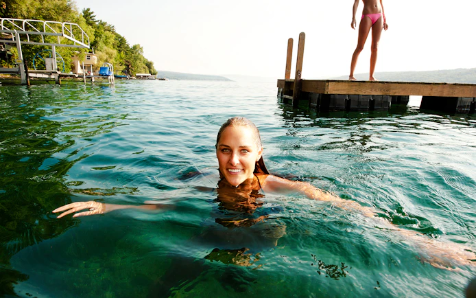 Swimming in Shala River near a wooden dock, surrounded by lush greenery.