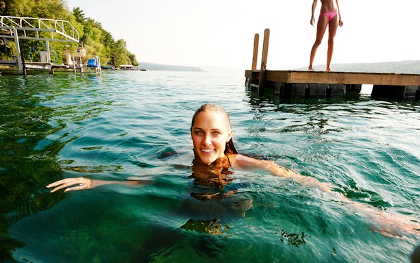 Swimming in Shala River near a wooden dock, surrounded by lush greenery.