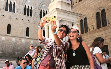 Tourists taking a selfie in front of historic architecture in San Gimignano, Italy.