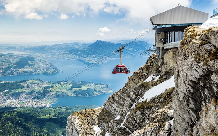 Cable car ascending from Kriens to Mount Pilatus with scenic view of Lake Lucerne.