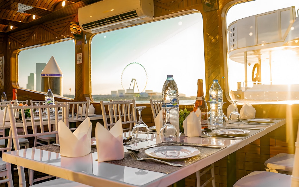 Dhow cruise dining setup with Dubai skyline and Ferris wheel view.