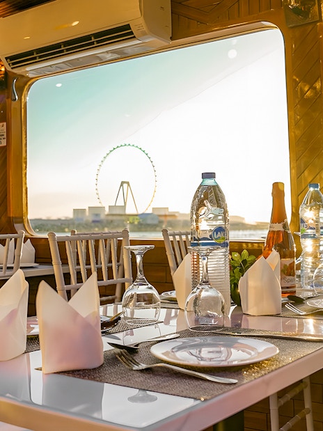 Dhow cruise dining setup with Dubai skyline and Ferris wheel view.