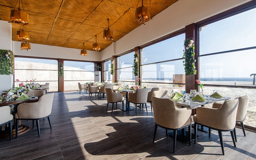 Dining area with ocean view at Al Majles Resort, featuring elegant table settings and large windows.