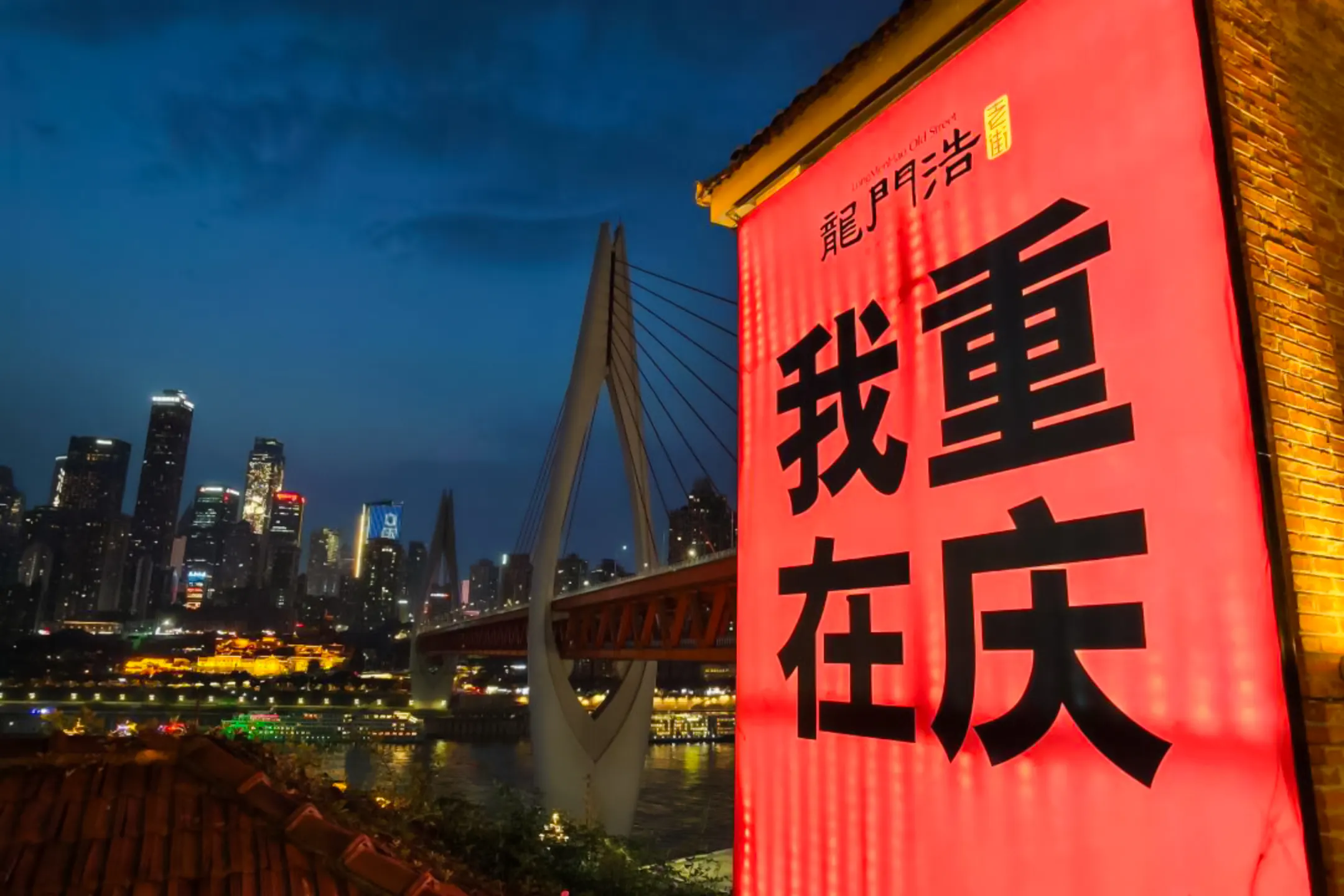 Chongqing skyline at night with illuminated bridge and Longmenhao sign.
