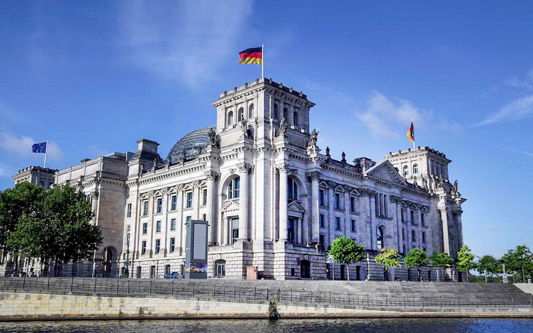 Reichstag building in Berlin with German flag on top.