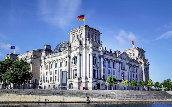 Reichstag building in Berlin with German flag on top.
