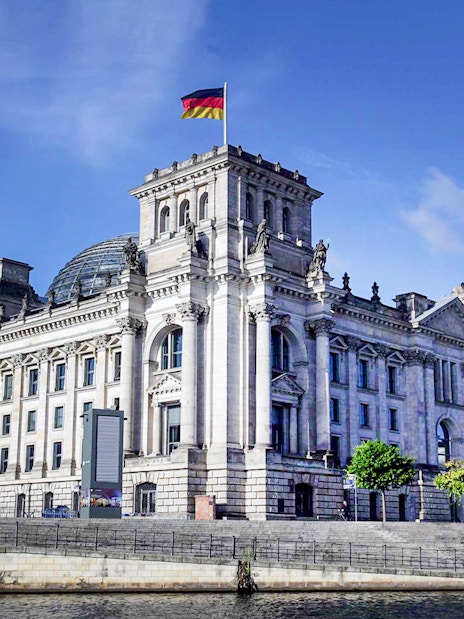 Reichstag building in Berlin with German flag on top.