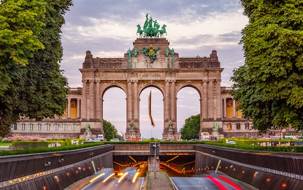 Triumphal Arch at Parc du Cinquantenaire in Brussels at dusk with light trails.