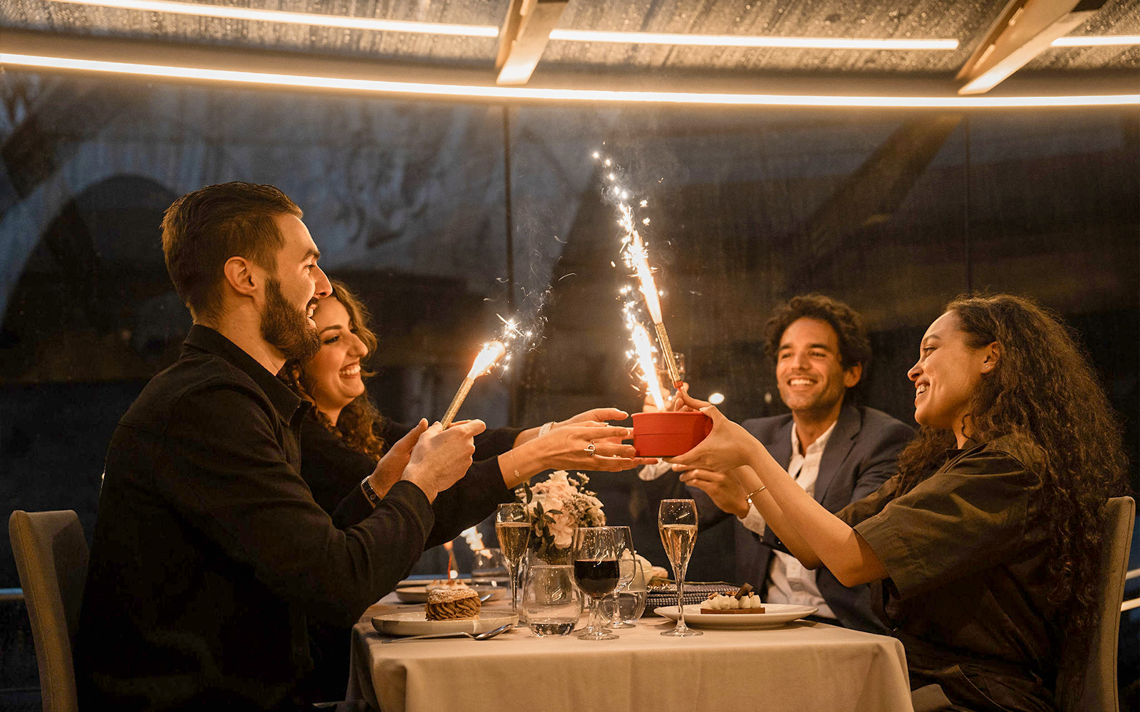 Guests enjoying a festive dinner with sparklers on a Seine River cruise in Paris.