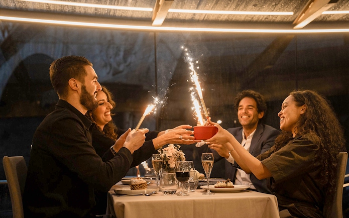 Guests enjoying a festive dinner with sparklers on a Seine River cruise in Paris.
