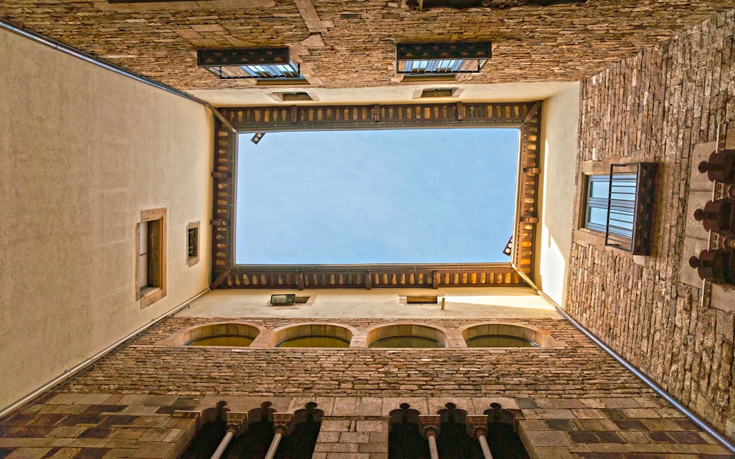 Courtyard view of the Picasso Museum in Barcelona, showcasing stone walls and blue sky.