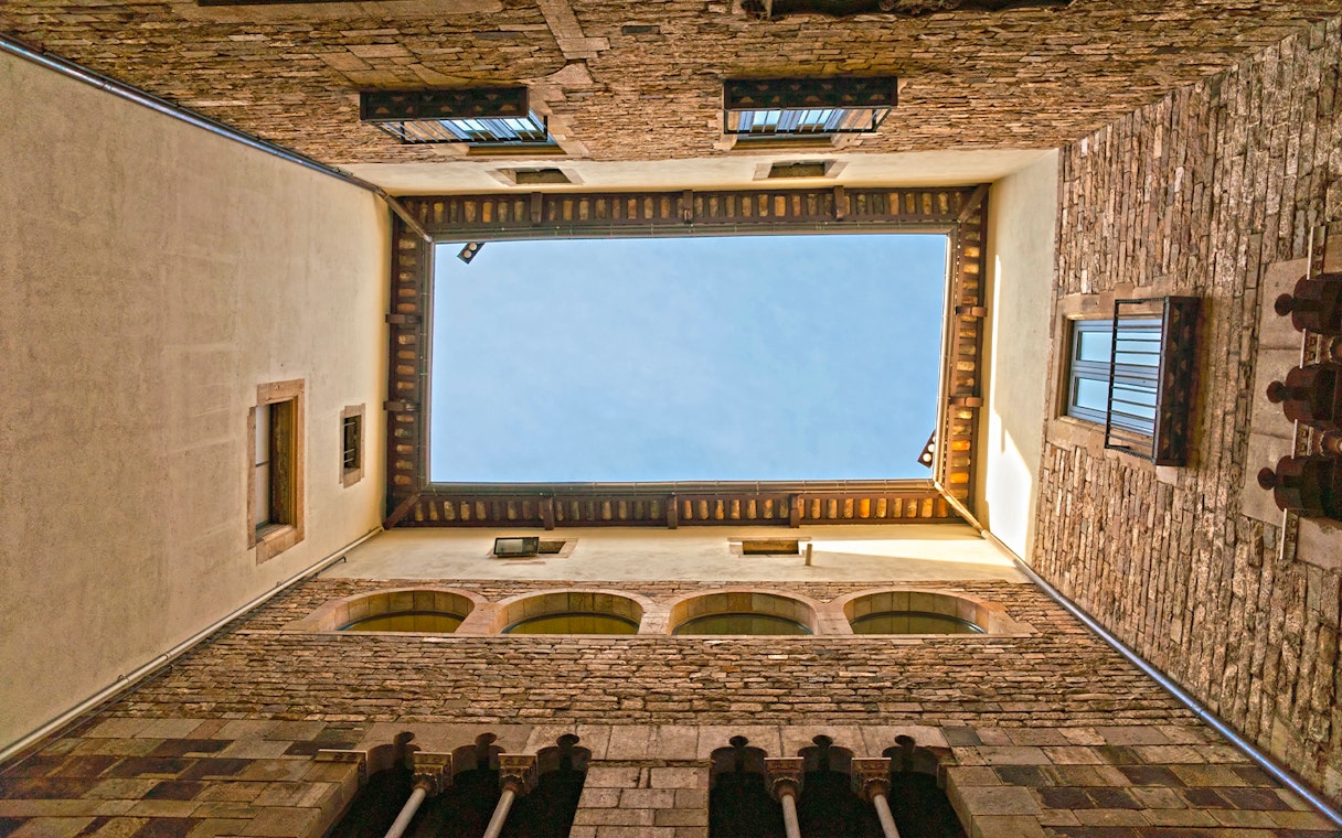 Courtyard view of the Picasso Museum in Barcelona, showcasing stone walls and blue sky.