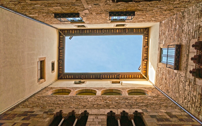 Courtyard view of the Picasso Museum in Barcelona, showcasing stone walls and blue sky.