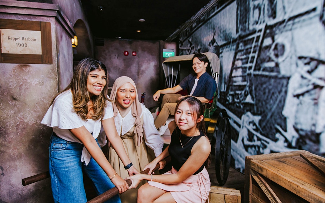 Visitors engaging with a historical rickshaw exhibit at Madame Tussauds Singapore.