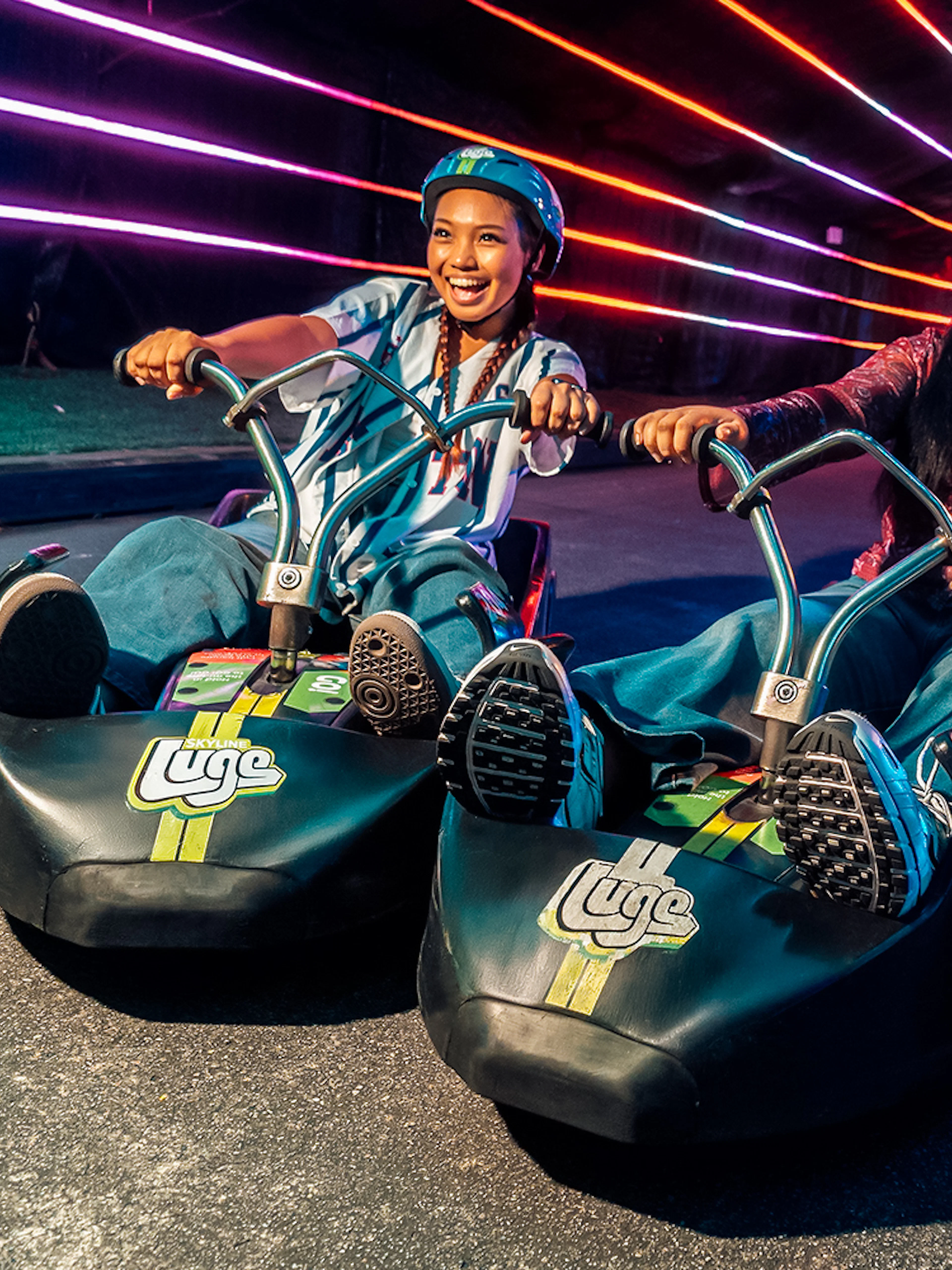 Friends enjoying night luge ride under colorful lights in Singapore.