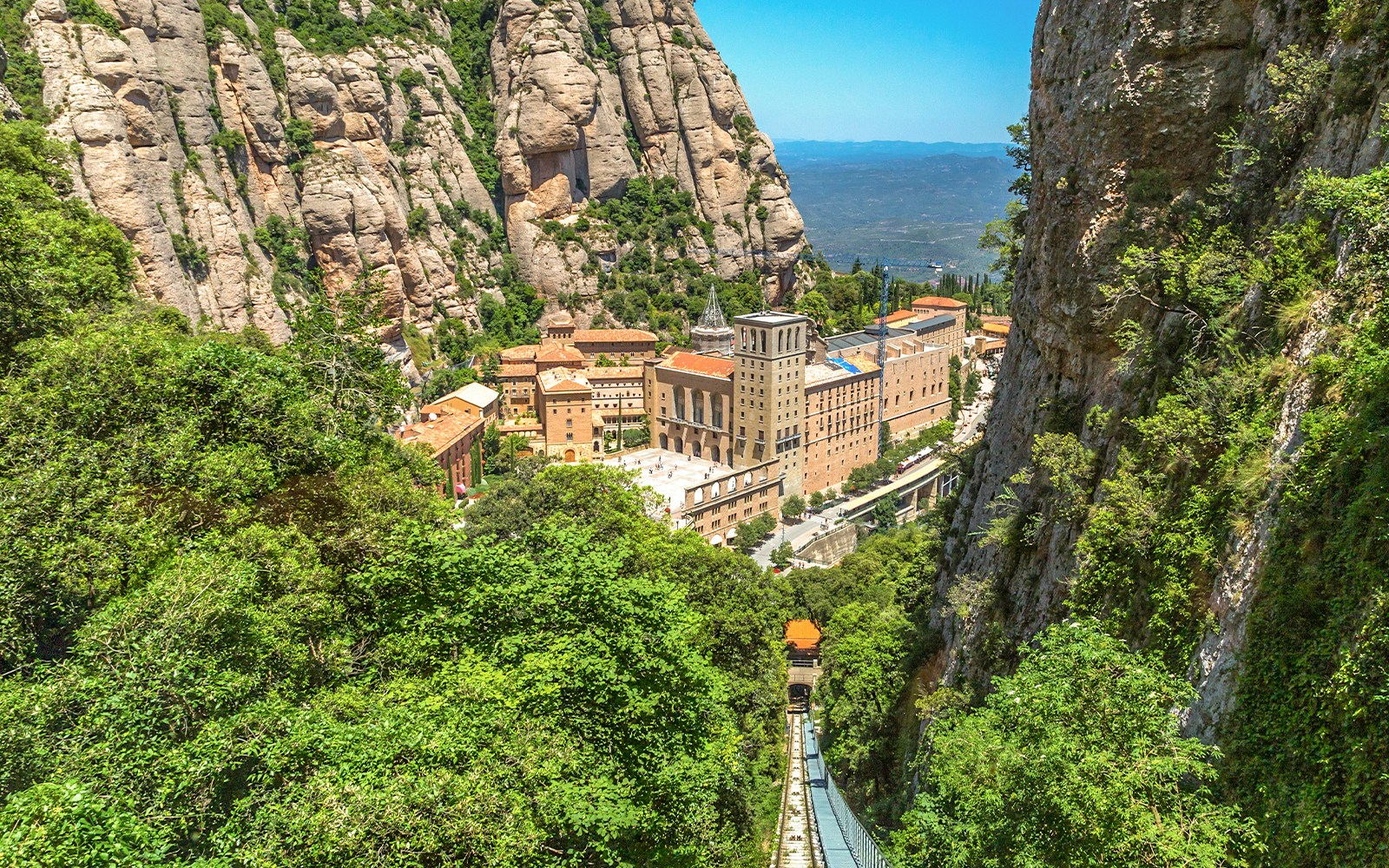Montserrat monastery with funicular railway in the foreground, nestled in the rugged Catalonian mountains.
