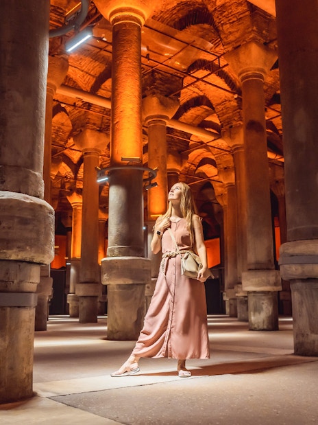 Woman exploring the illuminated columns inside the Basilica Cistern, Istanbul.