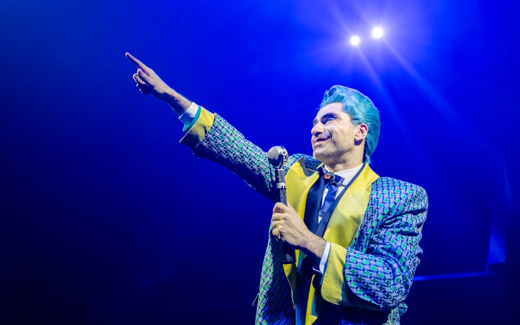 Performer in colorful costume on stage during Hunger Games West End show.