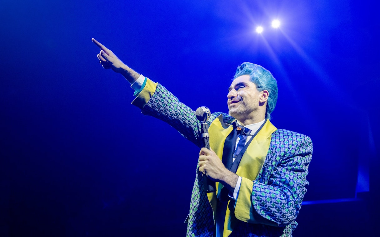 Performer in colorful costume on stage during Hunger Games West End show.