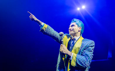 Performer in colorful costume on stage during Hunger Games West End show.