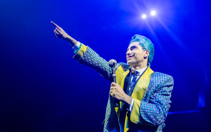 Performer in colorful costume on stage during Hunger Games West End show.