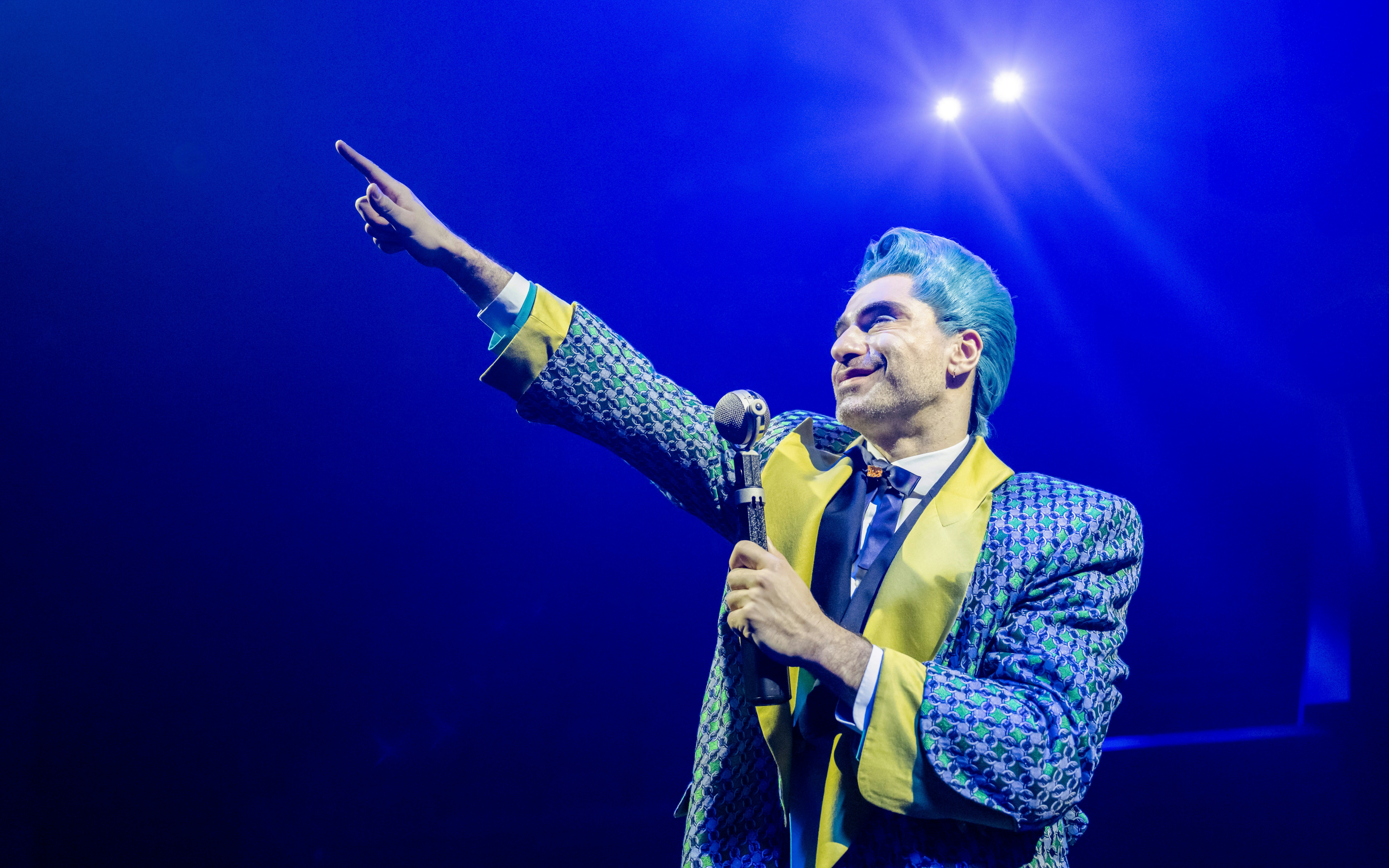 Performer in colorful costume on stage during Hunger Games West End show.