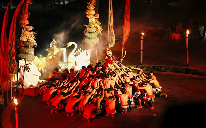 Kecak and Fire Dance performance at Melasti Beach, Bali, with dancers in a circle.