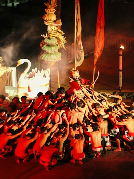 Kecak and Fire Dance performance at Melasti Beach, Bali, with dancers in a circle.