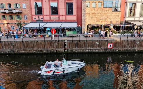 Guests navigating a self-drive electric boat along the waterfront in Gdansk.