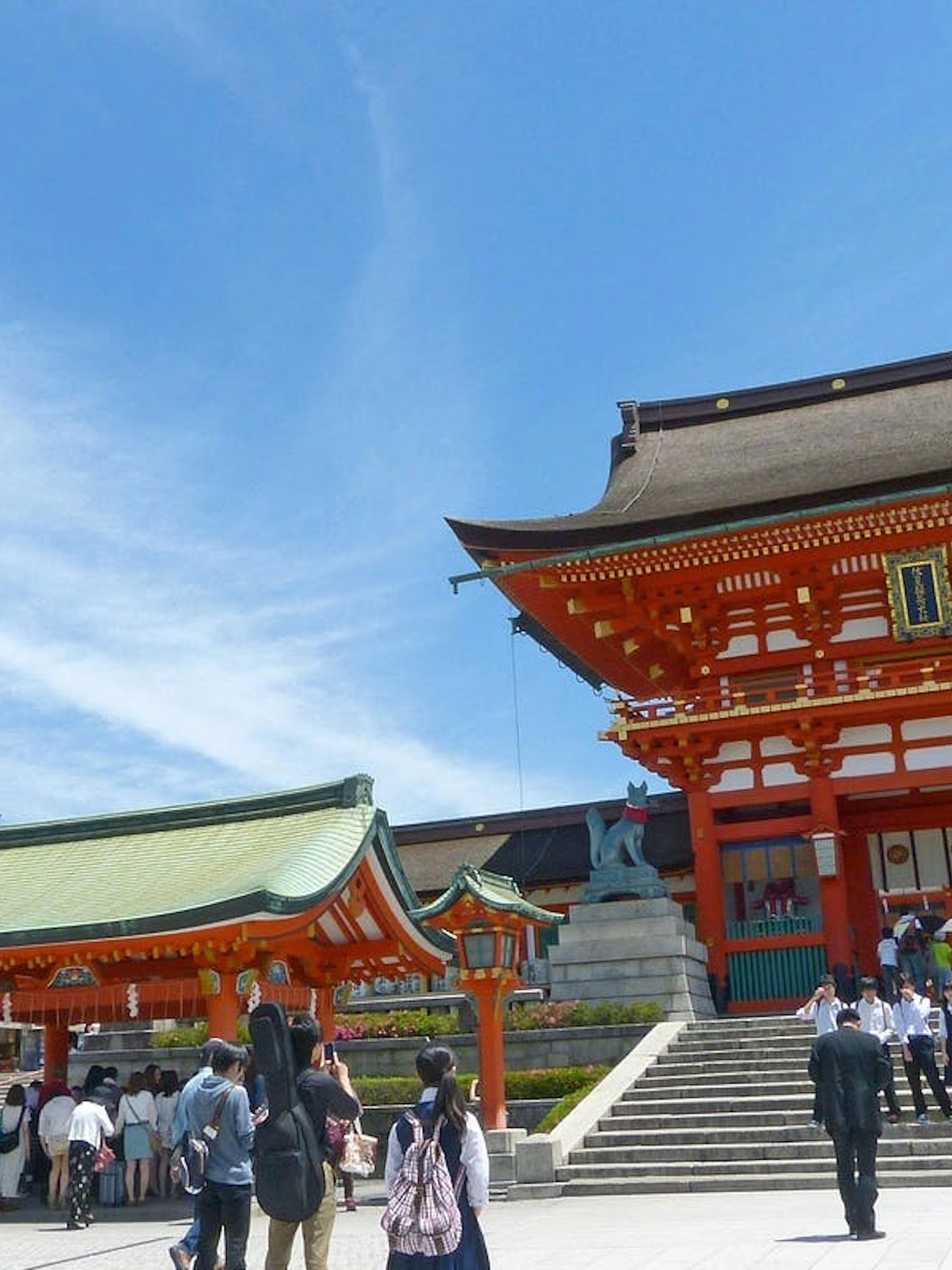 Visitors at Hase-dera Temple entrance in Kamakura, Japan, under a clear blue sky.