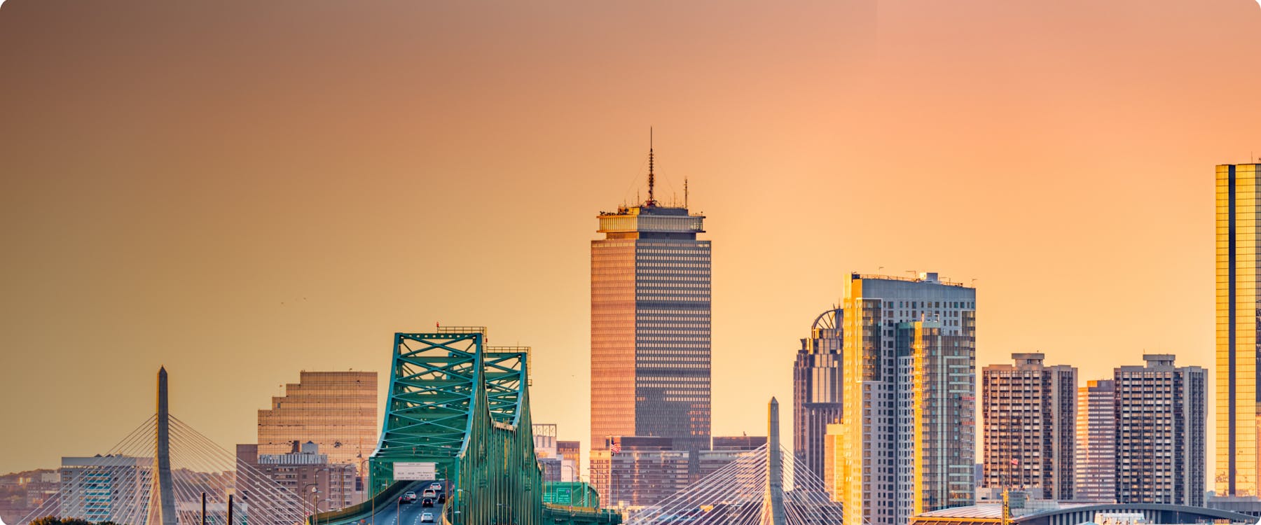 Boston skyline with Zakim Bridge and Prudential Tower at sunset.