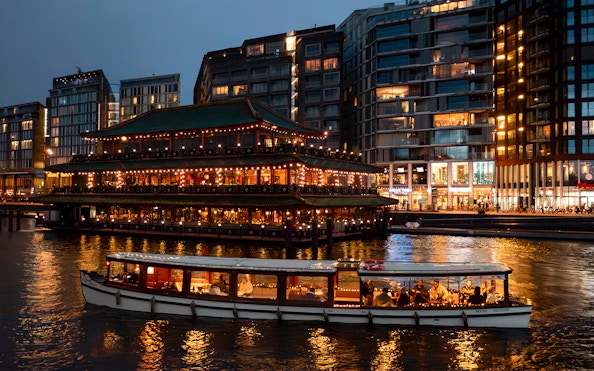 Cruise boat passing illuminated building during Amsterdam Light Festival.