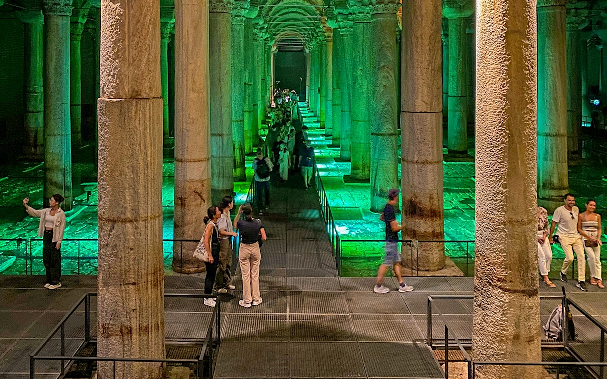 Tourists exploring the illuminated Basilica Cistern in Istanbul during an Old City Walking tour.